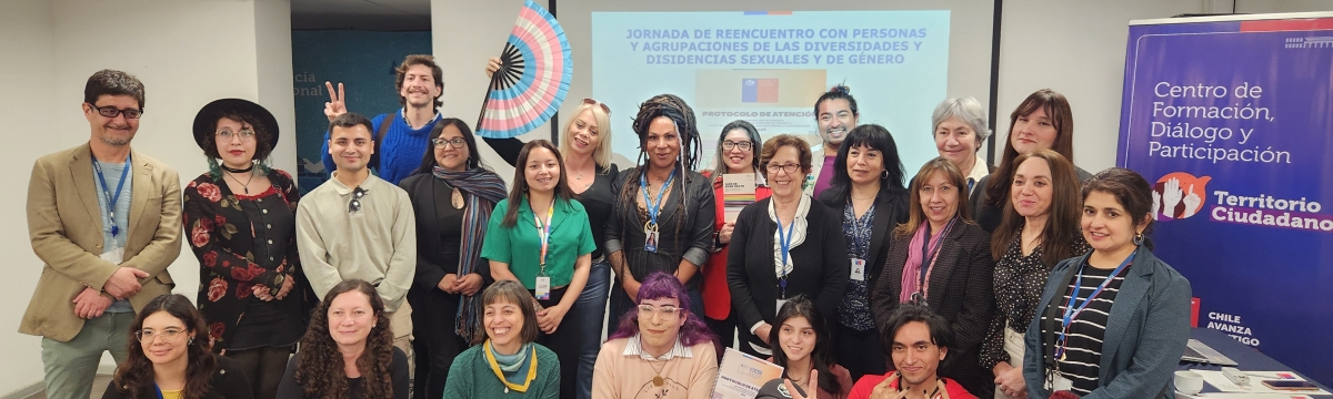 Grupo de personas de pie y en cuclillas en un salón mirando a cámara