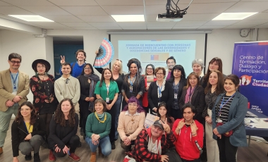 Grupo de personas de pie y en cuclillas en un salón mirando a cámara