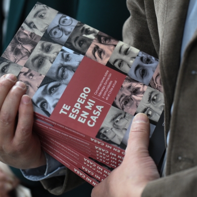 Las manos de una persona sostienen un montón de copias del libro "Te espero en mi casa"